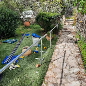 מעקה מתכת מותקן בגינה עם כלים וחומרים מסביב