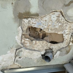 קיר עם חור גדול וצינור מתכת חשוף