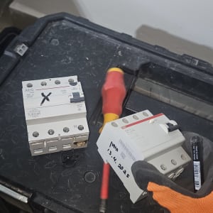 מפסק חשמלי, מברג, כפפה כתומה על רקע קופסה שחורה