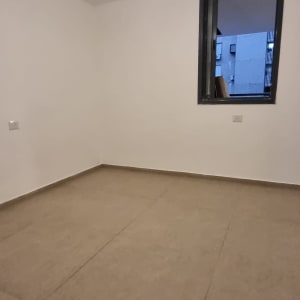 חדר ריק עם רצפת אריחים וחלון פתוח