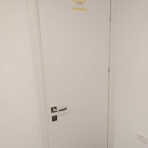 דלת לבנה עם ידית מתכת על קיר לבן