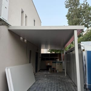 פרגולה מאלומיניום מותקנת בחצר עם לוחות קיר