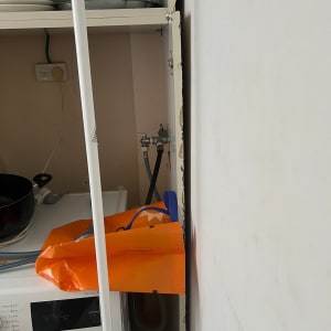 ארון פתוח עם כלים, מכונת כביסה ושקית כתומה