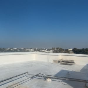 גג אטום עם ציפוי לבן ומעקה בטון