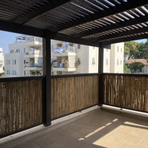פרגולה מעץ עם גדר במבוק במרפסת