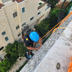 אדם עם קסדה כחולה עובד בגובה על חבל