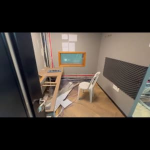 חדר עם כיסא פלסטיק, שולחן עץ, לוחות קיר, חוטים חשופים