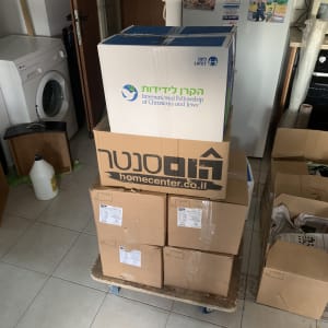 קופסאות קרטון על עגלה בחדר עם מכונת כביסה