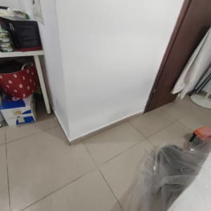 פינה של חדר עם קיר לבן ורצפת אריחים