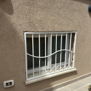 חלון עם סורגים לבנים על קיר חום