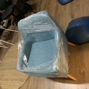 כיסא כחול עטוף בניילון על רצפת עץ