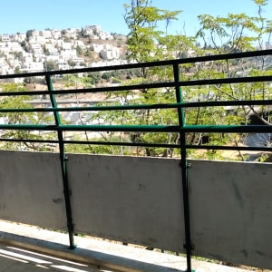 מעקה מתכת עם נוף עירוני ועצים ברקע
