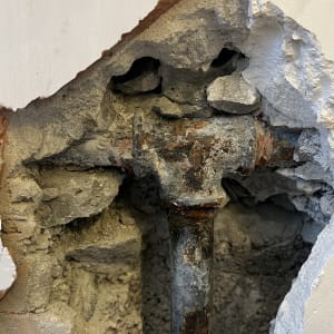 צינור חלוד בקיר עם טיח מתקלף