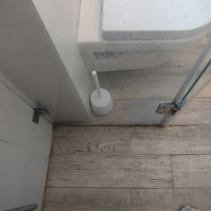 מקלחון עם דלת זכוכית ומברשת ניקוי לבנה