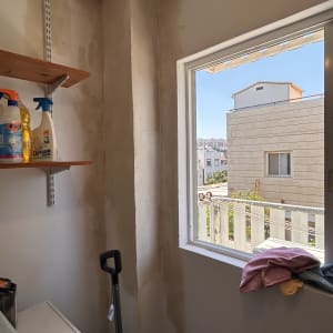 יישום והחלקת שפכטל על קירות וקורות בחדר שירות לפני צביעה