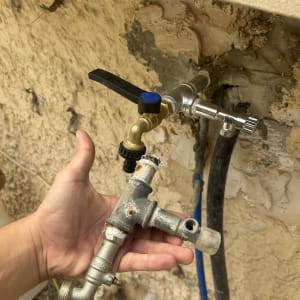 ברזים וצינורות על קיר חיצוני עם יד מחזיקה