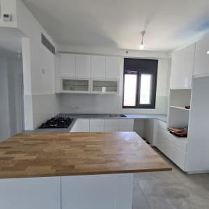 מטבח חדש עם ארונות לבנים ומשטח עץ