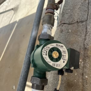 משאבה ירוקה מחוברת לצינור מתכת על קיר בטון