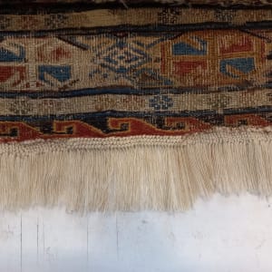 שטיח עם דוגמאות צבעוניות וגדילים לבנים