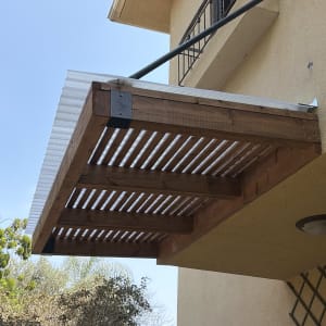 פרגולה מעץ מחוברת לקיר בית