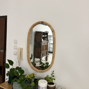 מראה עגולה תלויה על קיר לבן עם שולחן עץ מתחתיה.