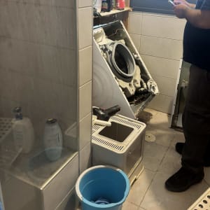 אדם מתקן מכונת כביסה בחדר אמבטיה