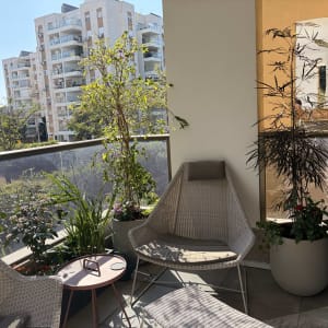 מרפסת עם צמחים ועציצים, כיסאות ושולחן קטן