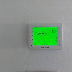 תרמוסטט דיגיטלי עם תצוגה ירוקה על קיר לבן