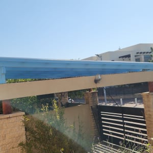 פרגולה מעץ צבועה בכחול עם עמודי אבן