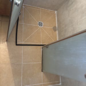 מקלחת עם דלת זכוכית ורצפת אריחים