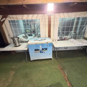 ציוד להשכרת אירועים כולל מקרר ומיחם על שולחנות מתקפלים