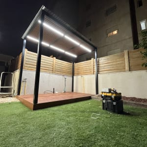 פרגולה מעץ עם תאורה על דשא סינתטי