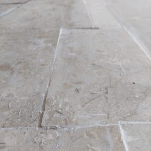 Close-up of tiled floor with grout lines visible, showing renovation work.