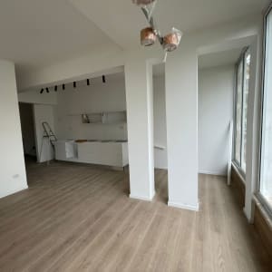 קירות גבס לבנים בחדר עם חלונות גדולים ורצפת עץ