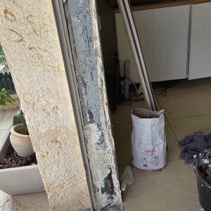 עבודת תיקון מסגרת אלומיניום ליד קיר אבן