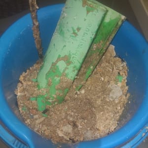 דלי כחול עם צינור ירוק ומעט חול