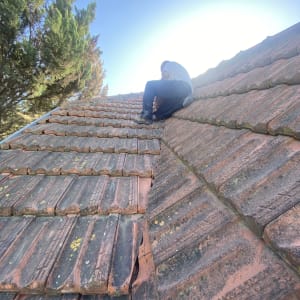 אדם מתקן רעפים על גג רעפים ישן