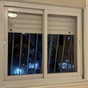 תריסים לבנים על חלון עם סורגים בלילה