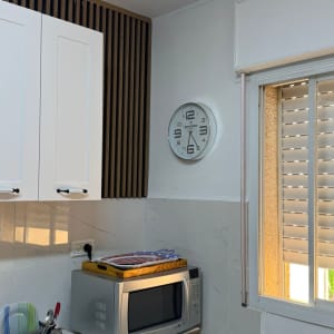 מטבח עם מיקרוגל, שעון קיר וארונות לבנים