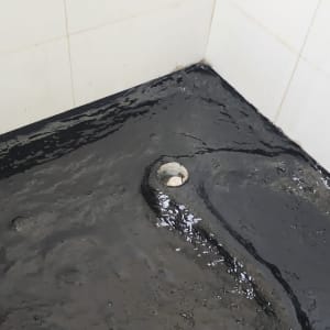 איטום רצפה עם חומר שחור סביב ניקוז