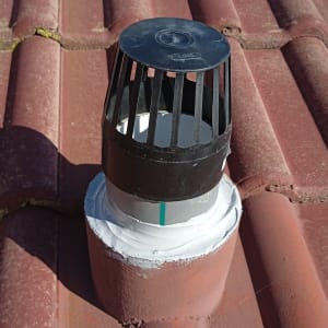 ארובה על גג רעפים אדום עם כיסוי שחור