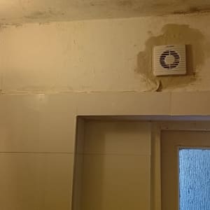 מנורה דולקת ומאוורר קיר בחדר אמבטיה