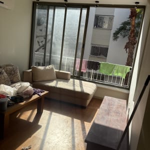 חדר עם ספה, שולחן וכביסה תלויה בחוץ