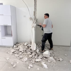 אדם מבצע עבודת שיפוץ עם קיר שבור וכלים