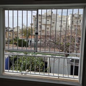 סורגי חלון עם נוף חיצוני של בניינים ועצים