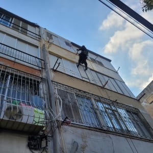 אדם תלוי על חבלים מבצע עבודות בגובה על בניין