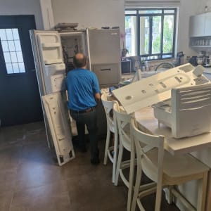 אדם מתקן מקרר במטבח עם חלקים מפורקים