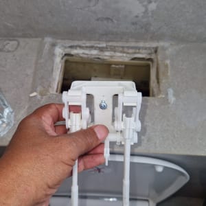 יד מחזיקה חלק פלסטיק מעל אסלה פתוחה