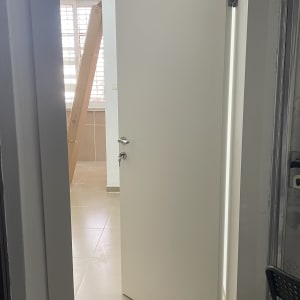 דלת לבנה פתוחה עם ידית מתכת ומנעול