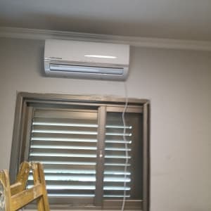 מזגן מותקן מעל חלון עם תריסים